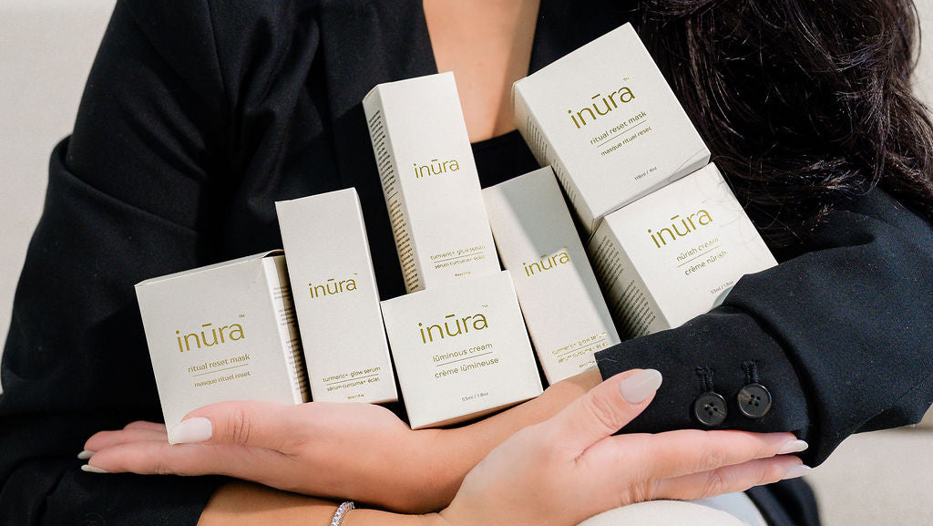 Hands cradling inūra skincare products and packaging to mark the brand’s registered trademark milestone.